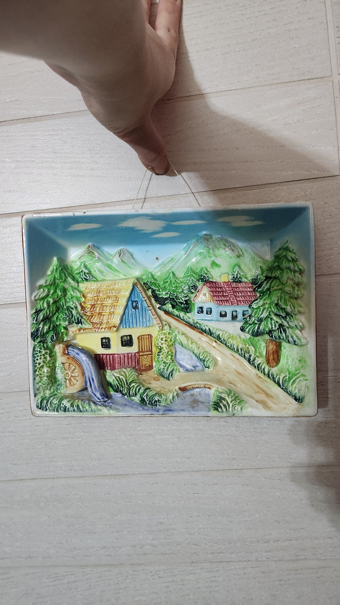 3D relief ceramic wall hanging depicting a hand-painted village scene