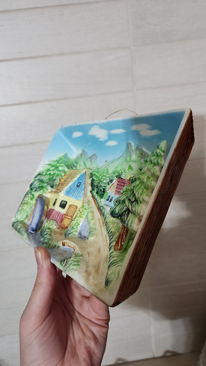 3D relief ceramic wall hanging depicting a hand-painted village scene