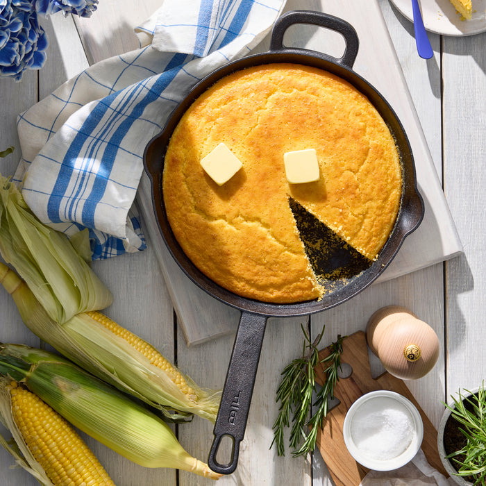 The Bobby Flay by GreenPan 4-Piece Cast Iron Set with Bobby at Home Cookbook features a spacious skillet, perfect for golden cornbread, and comes with stylish accessories—ideal for any modern kitchen.