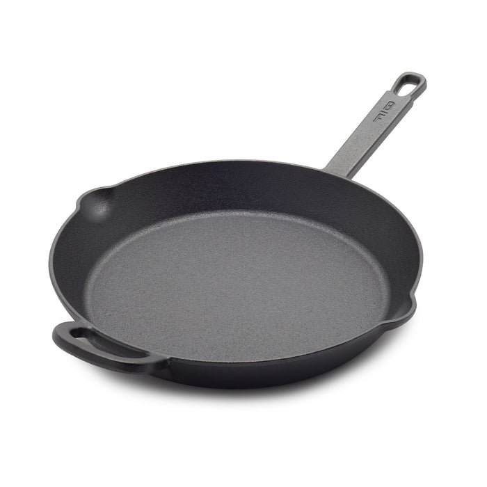 The Bobby Flay by GreenPan 12" Cast Iron Frypan, shown in black with a long handle, small helper handle, and two pour spouts on a white background, offers a spacious cooking surface—perfect for any meal.