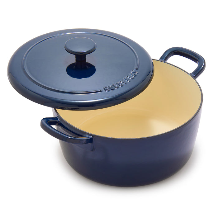 Cobalt blue enameled Dutch oven with lid slightly open, revealing its cream-colored interior.
