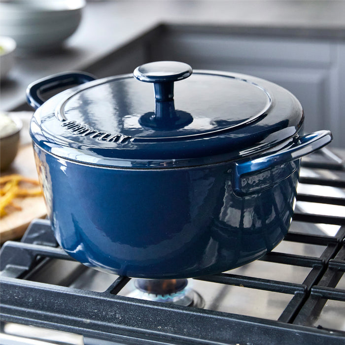 Cobalt blue Dutch oven with handles on a stove in a modern kitchen setting.