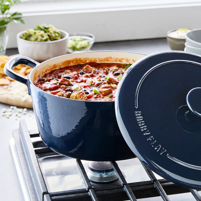 Cobalt blue Dutch oven with stew inside on a stove, lid placed next to it.