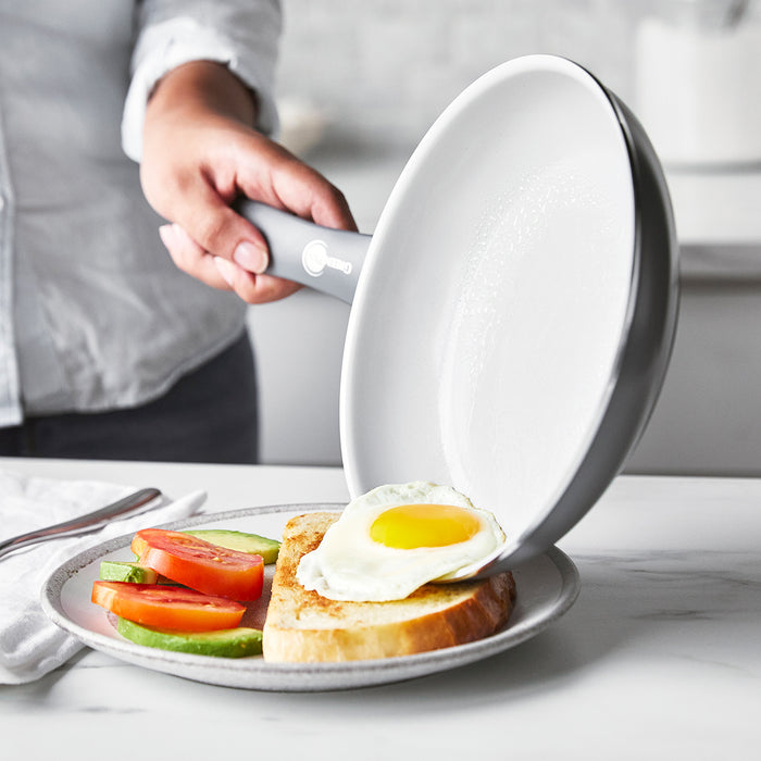 Sunny-side-up egg being slid from a Dover ceramic nonstick frypan onto avocado and tomato toast.