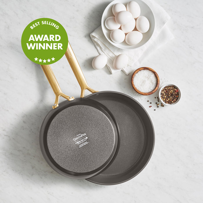 Two ceramic nonstick frypans, 9.5 and 11, with champagne handles, next to eggs, salt, and pepper.