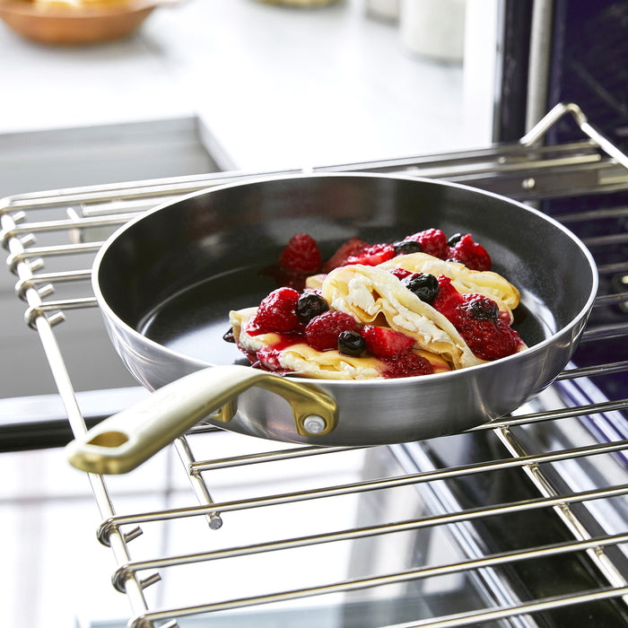 Set of two stainless steel frypans, 10-inch and 12-inch, with metallic champagne-colored handles on a plain background.