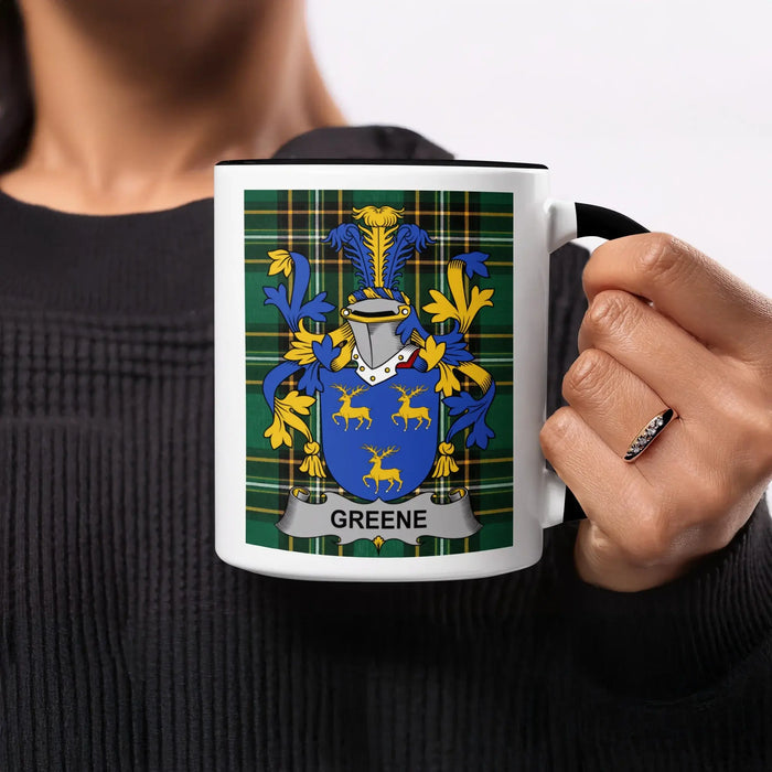 Coats of arms with "Greene" text on a white mug held by a person.