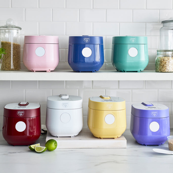 Pink 4-cup rice and grains cooker with ceramic pot on a countertop.