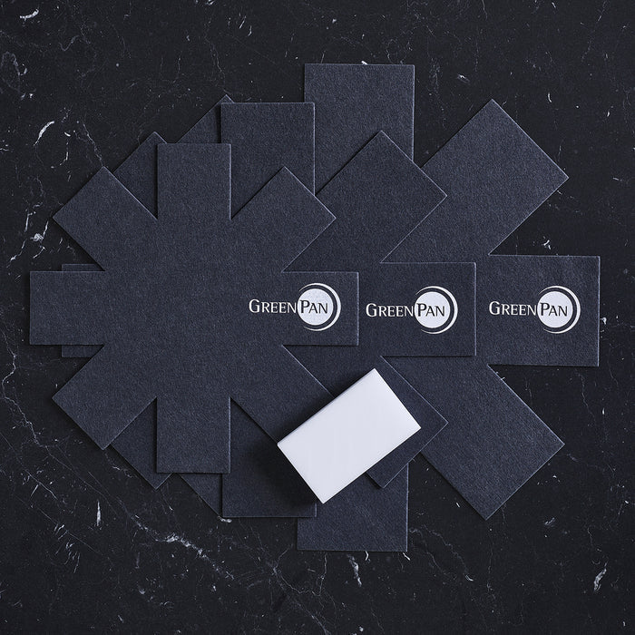 GreenPan 3 Pan Protectors, featuring the GreenPan logo, are displayed on a black marble surface. They offer reliable scratch protection for your nonstick pans. A small white rectangular item, likely packaging or padding, is also shown in front.