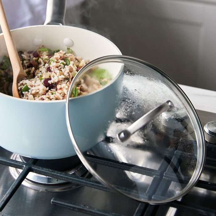 GreenPan glass lid set with two lids 8 and 10 beside a pot of rice and vegetables on a stove.