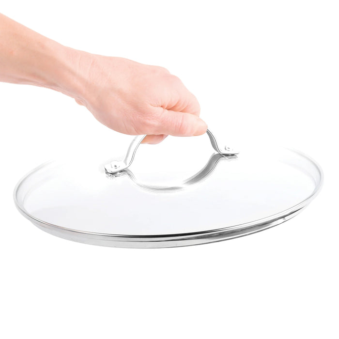 Hand holding an 8-inch glass pan lid with a stainless steel handle, shown against a white background.
