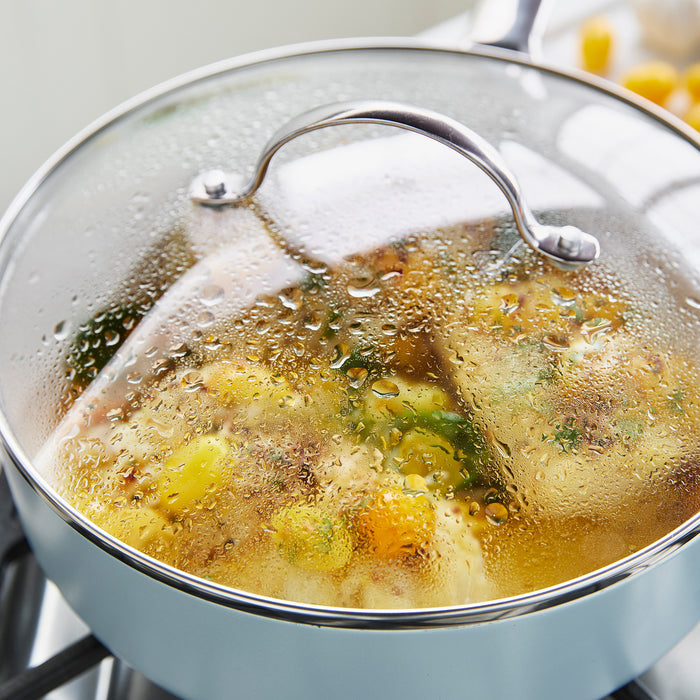 Boiling pot of soup with vegetables and dumplings on a stove