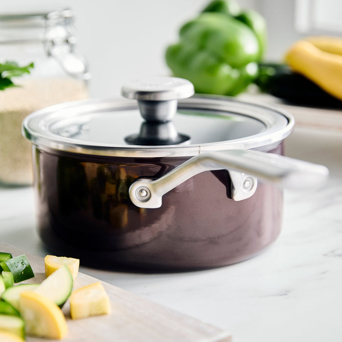 Chocolate brown enameled steel 2-quart saucepan with lid on a kitchen counter.