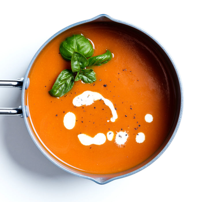 Navy ceramic nonstick 1-quart saucepan filled with tomato soup, cream, black pepper, and basil.