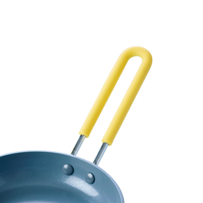 Small ceramic 5-inch frypan with a yellow handle on a white background, shown in close-up.