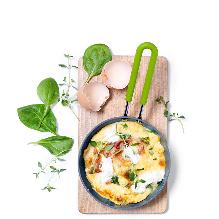 Mini green ceramic nonstick frypan with a spinach and herb omelette, viewed from above.