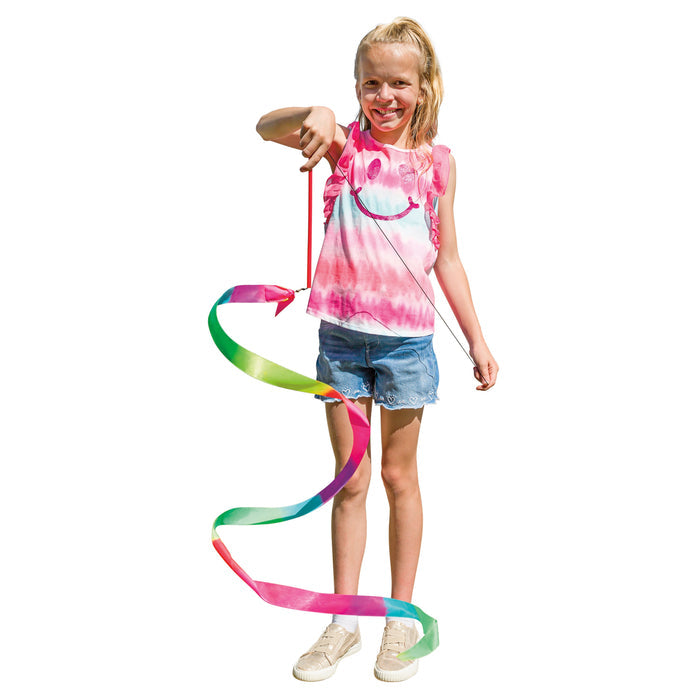 A smiling girl in a pink tie-dye tank top and denim shorts showcases the Playground Classics Rainbow Stunt Streamer, making colorful loops against a white background and celebrating the fun of creative movement.