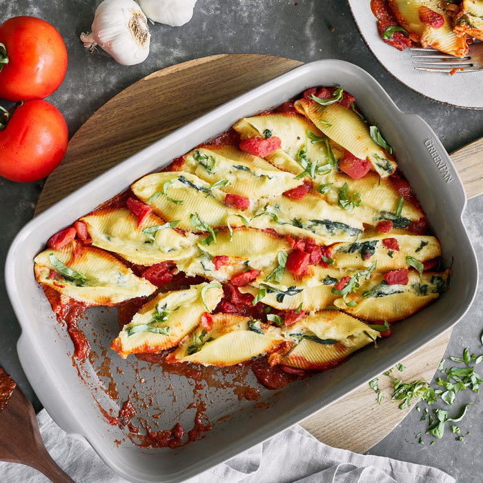 Stuffed pasta shells with red sauce in a white rectangular ceramic nonstick baker, 13x9, shown from above.