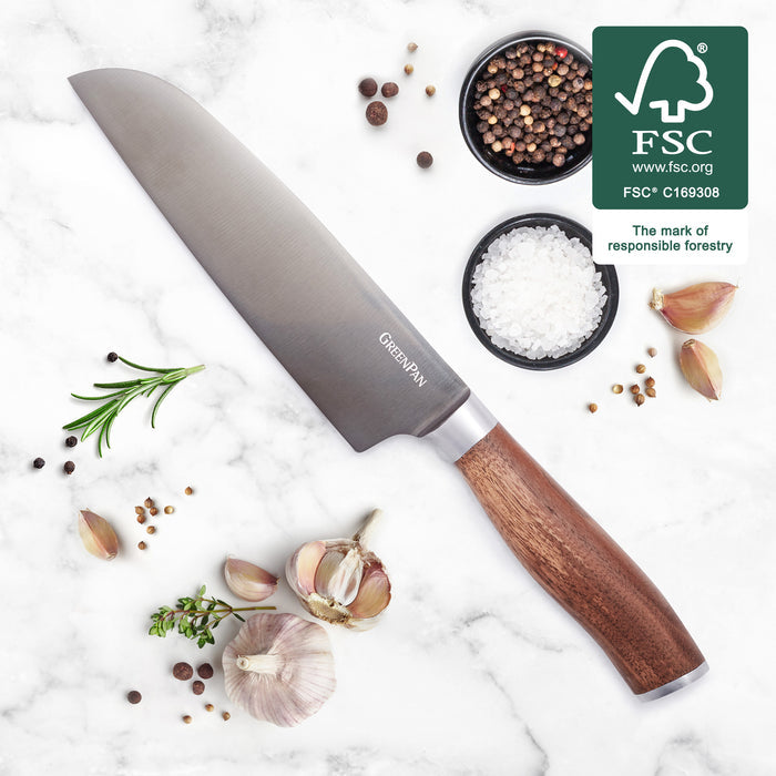 7 Santoku knife with titanium blade and walnut handle on white surface, herbs and FSC logo nearby.