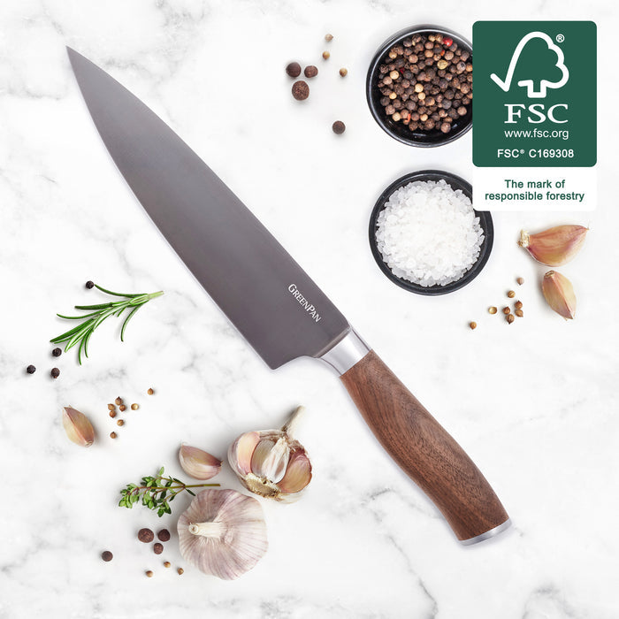 Chef’s knife with titanium blade and walnut handle on marble, shown with garlic, salt, peppercorns, rosemary, and FSC logo.