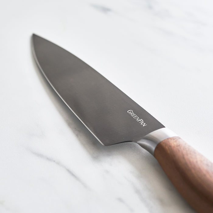 Chefs knife with a walnut handle on a white marble surface.