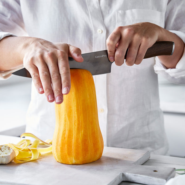 Slicing butternut squash with an 8 Premiere Titanium chefs knife; peels and garlic visible nearby.