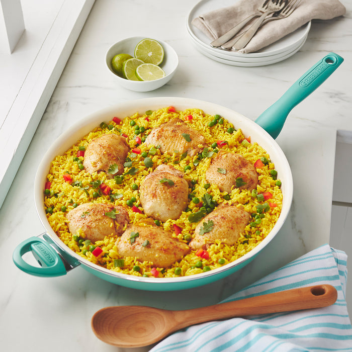 Turquoise ceramic nonstick 13.5 frypan with yellow rice, vegetables, and chicken on a white countertop.