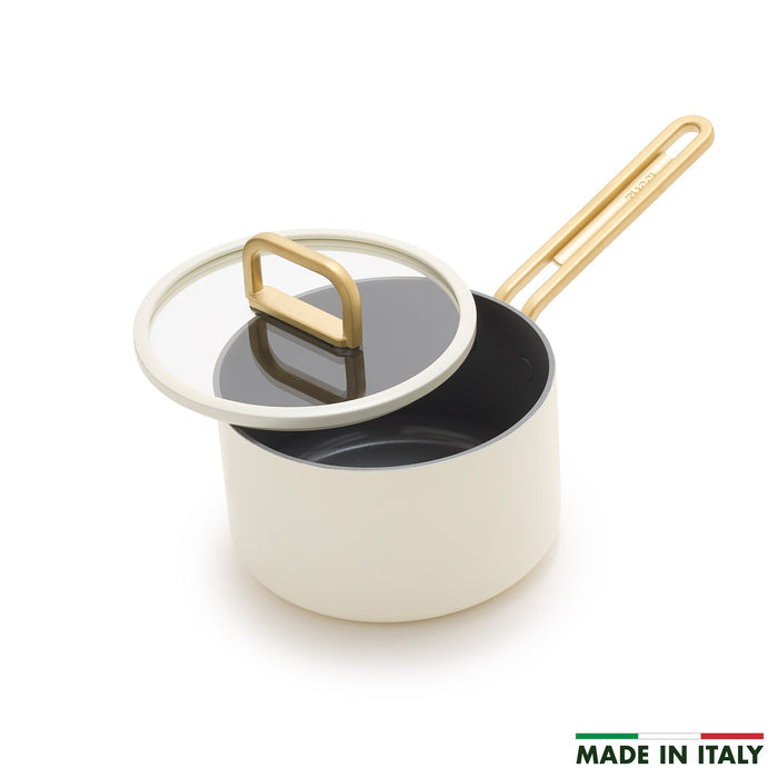 White ceramic nonstick saucepan with gold handle and glass lid, 2-quart size, shown at an angle.
