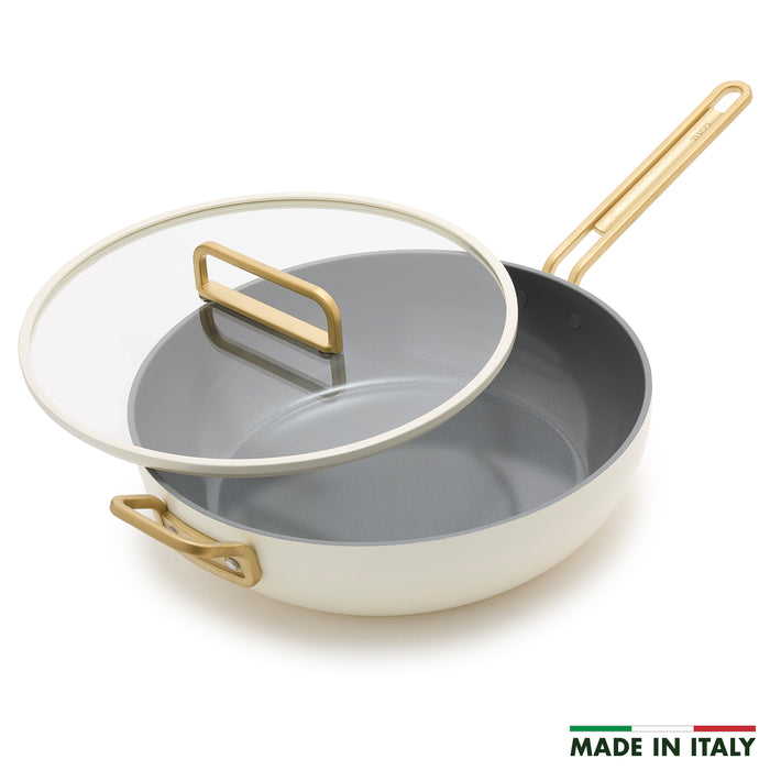 White ceramic 6.5-quart pan with gold handles and a glass lid.