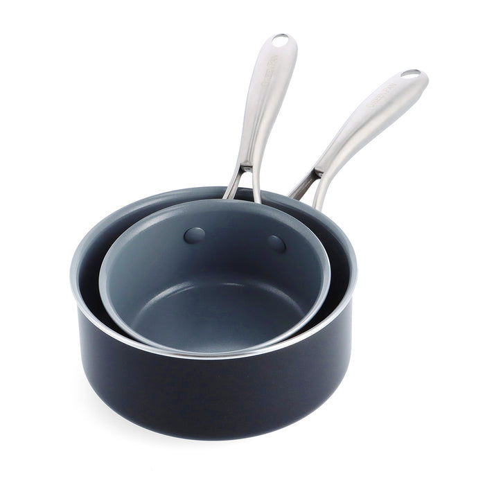 Two cream-colored ceramic saucepans, 1-quart and 2-quart, nest together with stainless steel handles and smooth rims.