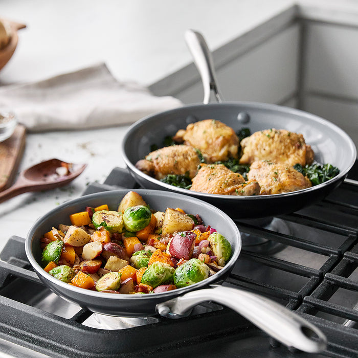 Two ceramic nonstick frypans, one with roasted chicken and greens, the other with sautéed vegetables. Set of two.