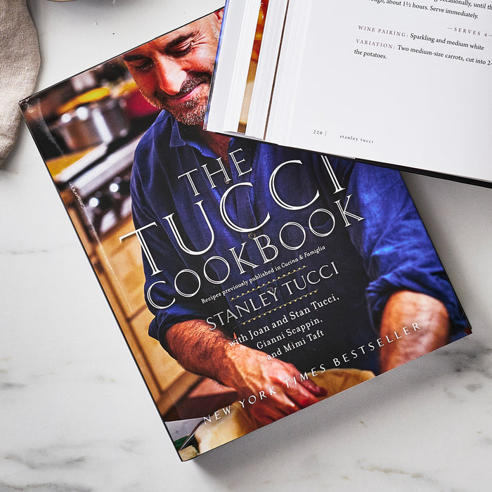 The Tucci Cookbook next to an open book on a flat surface, both books showing pages.