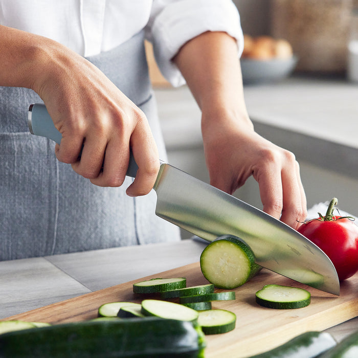 Slicing a cucumber with a Titanium Cutlery Ultimate knife from the Blue Haze block on a wooden cutting board.