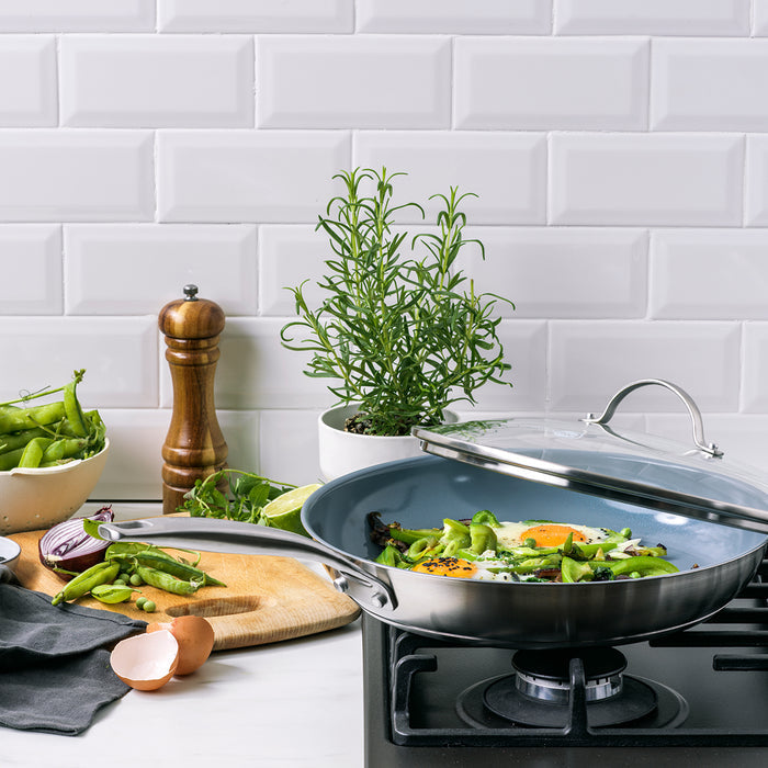 Stainless steel ceramic 12-inch frypan with lid, cooking eggs and vegetables, surrounded by fresh produce.