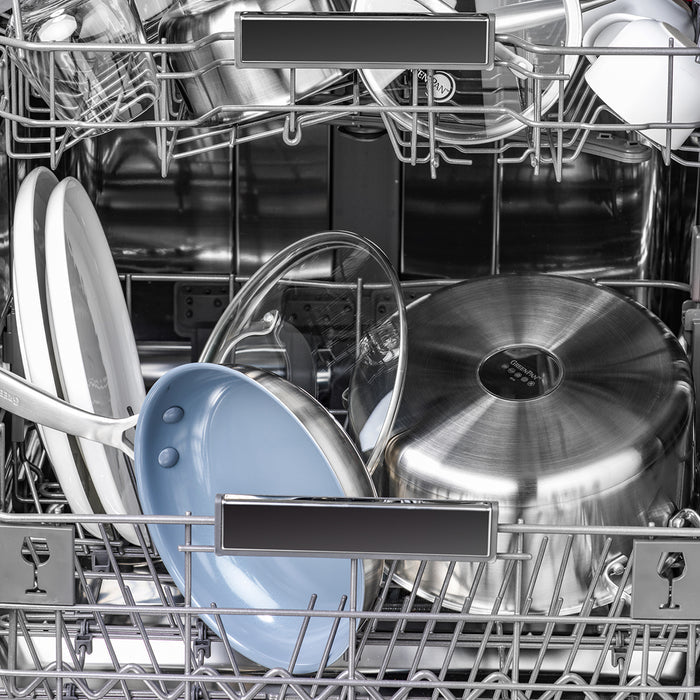 Stainless steel nonstick frypan with lid in an open dishwasher, ready for cleaning.