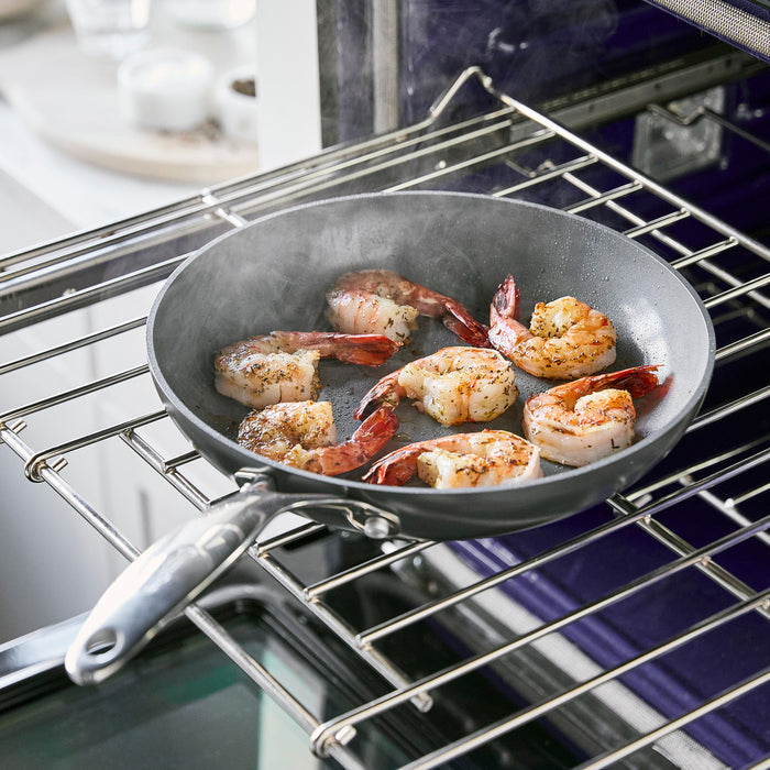 Shrimp cooking in a ceramic nonstick frypan on an oven rack, steam visible above the pan.