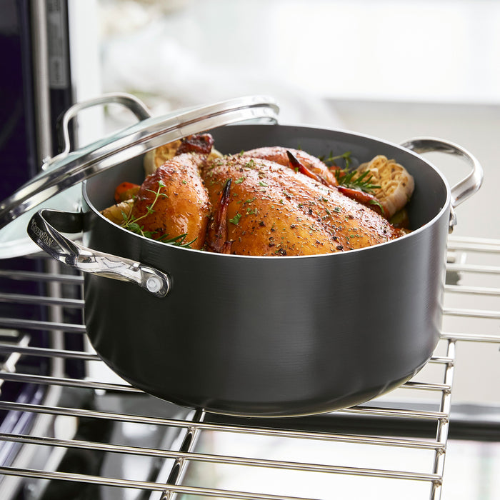 A whole roasted chicken seasoned with herbs sits in the Valencia Pro Ceramic Nonstick 5.5-Quart Stockpot with Lid, placed on an oven rack.
