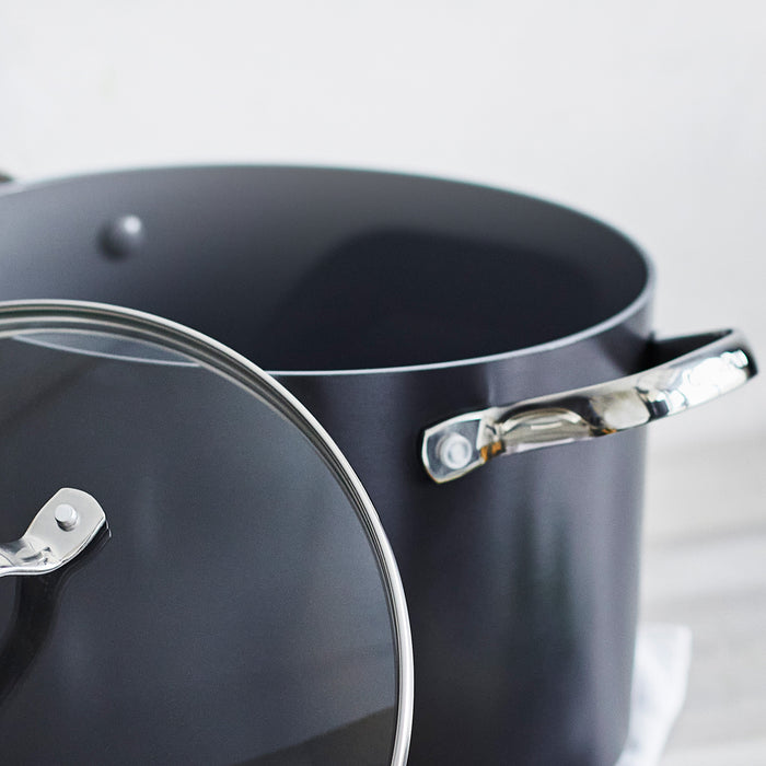Large ceramic nonstick stockpot with shiny metal handles and a glass lid, made from scratch-resistant aluminum.